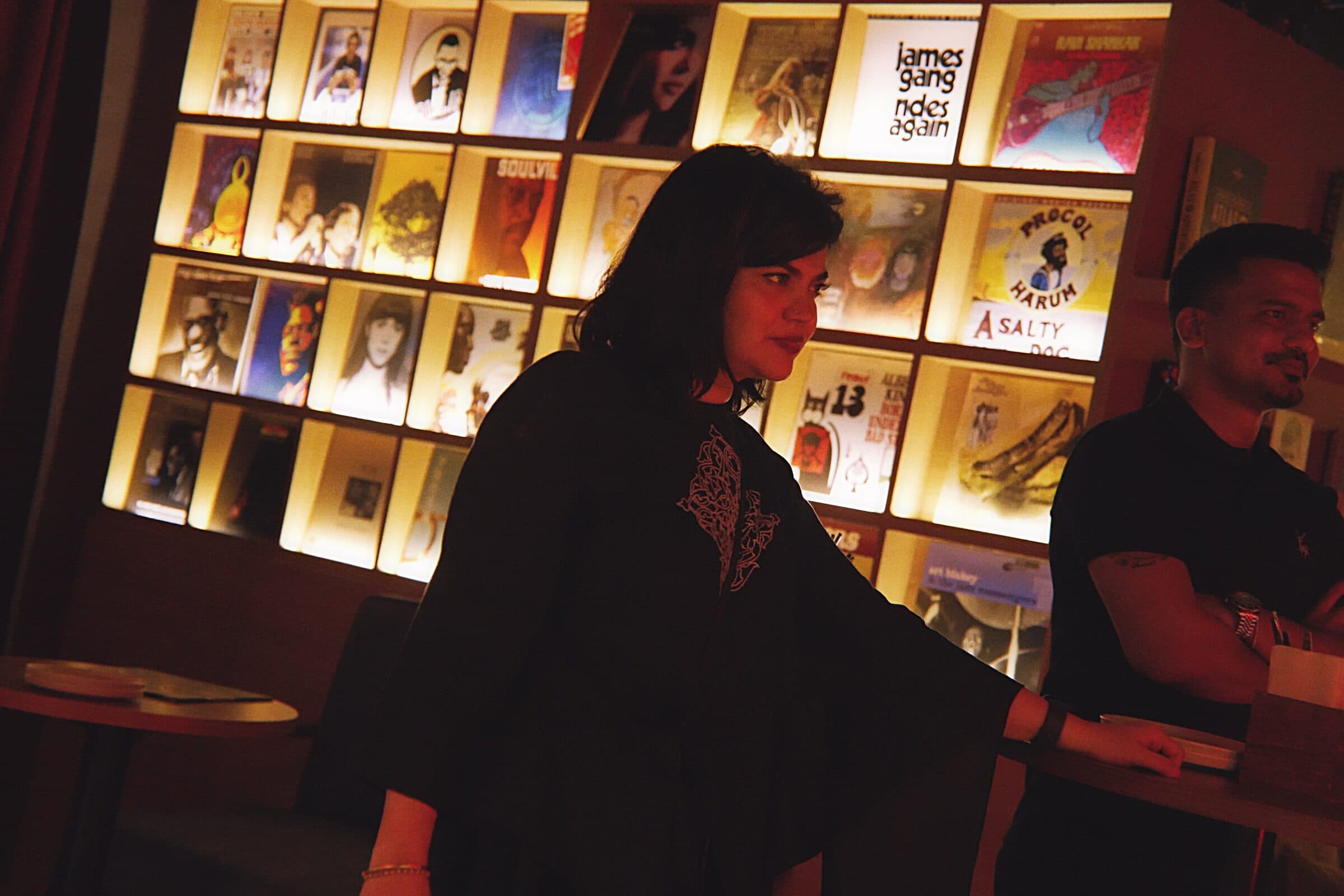 A guest by the backlit wall of record sleeves